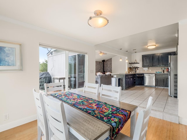 dining area featuring baseboards, ornamental molding, light wood-style floors, and a ceiling fan