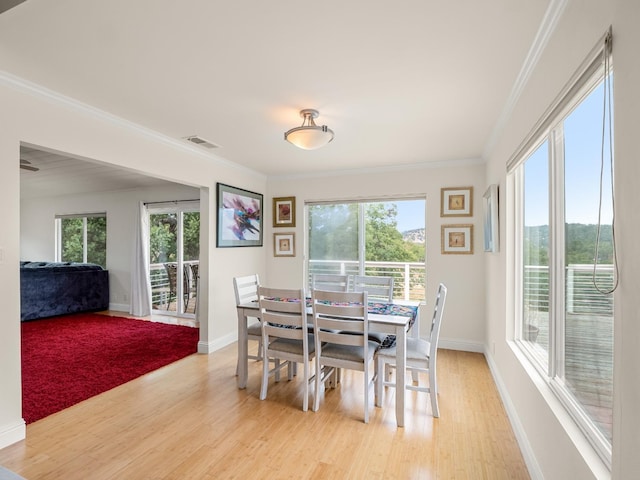 dining area featuring light wood-style floors, crown molding, and a wealth of natural light