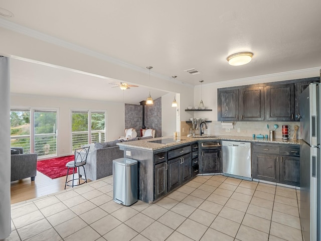 kitchen featuring a sink, a wood stove, stainless steel appliances, open floor plan, and visible vents