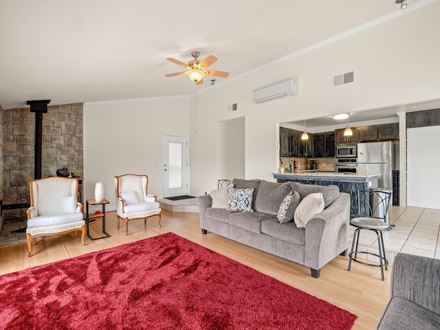 living room with crown molding, ceiling fan, a wood stove, visible vents, and a wall mounted AC