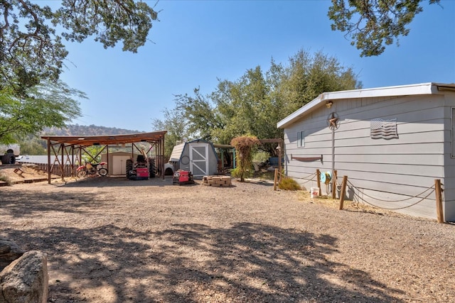 view of yard with an outdoor structure, a shed, and a carport