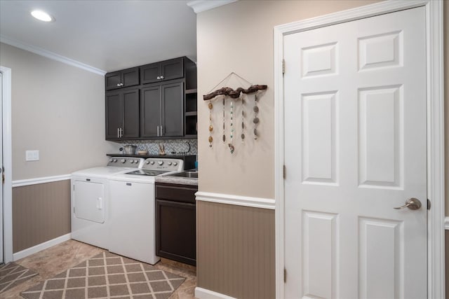clothes washing area with cabinet space, separate washer and dryer, wainscoting, and ornamental molding
