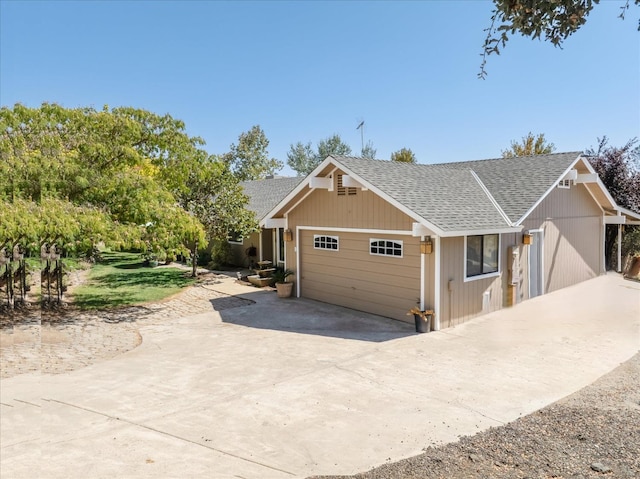 exterior space with an attached garage, a shingled roof, and concrete driveway