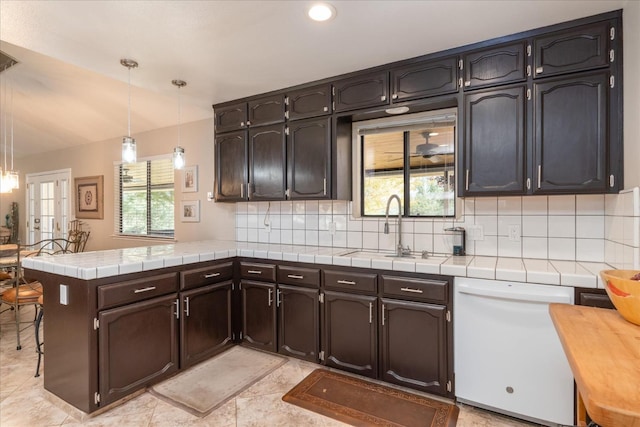 kitchen with a sink, tasteful backsplash, a peninsula, and dishwasher