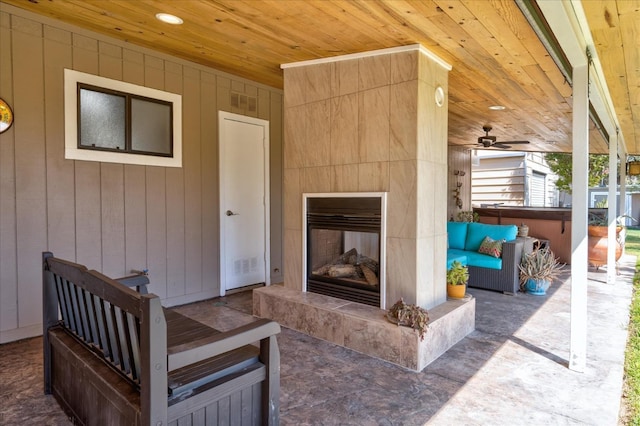 exterior space featuring a ceiling fan, a hot tub, an outdoor living space with a fireplace, and visible vents