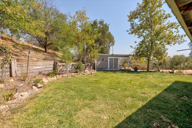 view of yard featuring fence, an outbuilding, and a storage shed