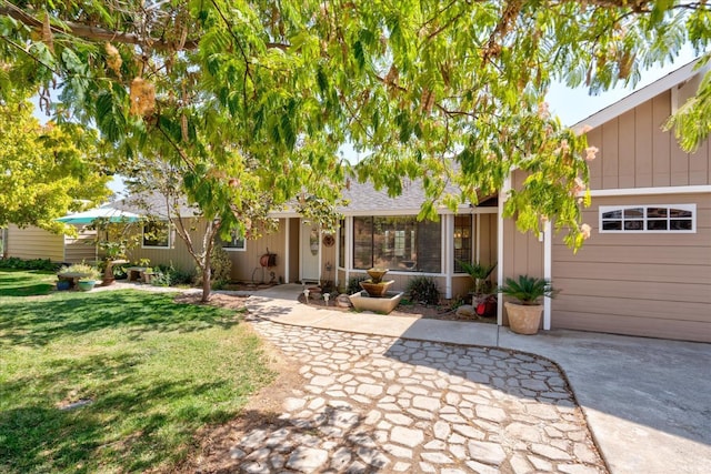 rear view of house with a garage, a yard, and driveway
