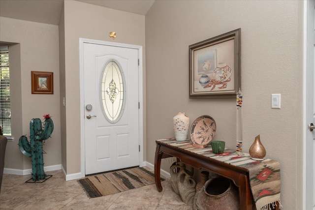 foyer entrance featuring light tile patterned flooring and baseboards