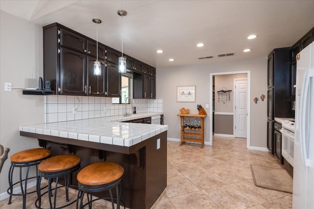 kitchen with baseboards, backsplash, a peninsula, and visible vents