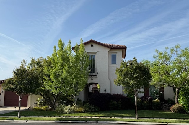 172 Omaha Ave, Clovis, CA 93619 - mediterranean / spanish-style home with stucco siding, a garage, a balcony, a front lawn, and a tile roof