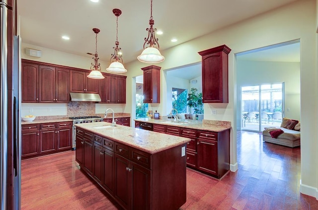 172 Omaha Ave, Clovis, CA 93619 - kitchen with under cabinet range hood, a sink, a center island with sink, refrigerator, and recessed lighting