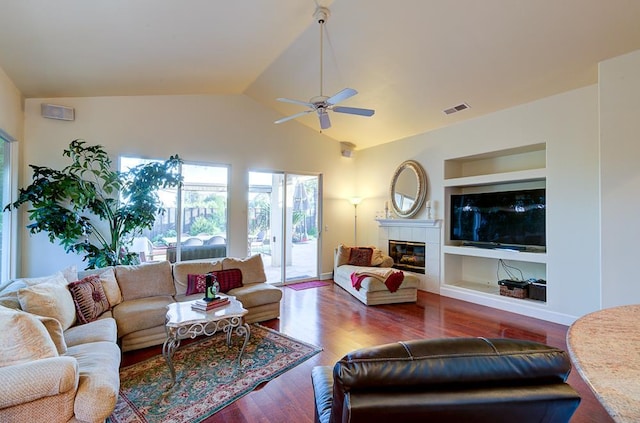 172 Omaha Ave, Clovis, CA 93619 - living room featuring ceiling fan, built in features, vaulted ceiling, wood finished floors, and a tiled fireplace