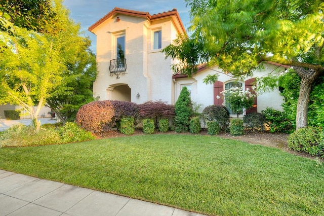 172 Omaha Ave, Clovis, CA 93619 - mediterranean / spanish-style house featuring stucco siding, a balcony, a front lawn, and a tiled roof