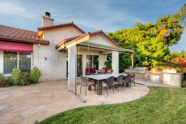172 Omaha Ave, Clovis, CA 93619 - back of property featuring exterior kitchen, a chimney, a patio area, stucco siding, and a lawn