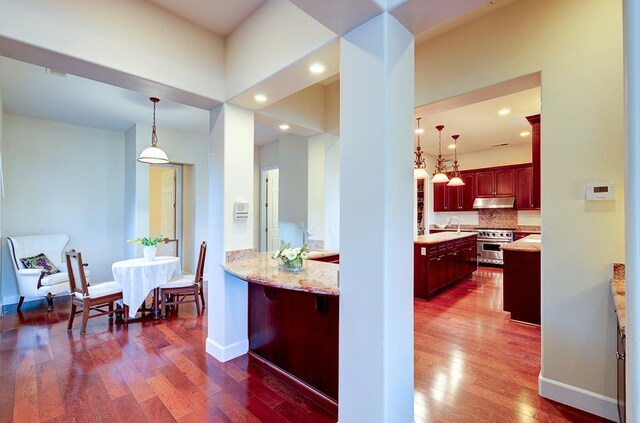 172 Omaha Ave, Clovis, CA 93619 - kitchen with under cabinet range hood, dark brown cabinets, stainless steel stove, dark wood-style flooring, and pendant lighting