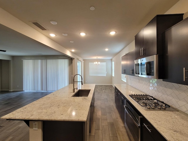 kitchen featuring dark wood-style flooring, a notable chandelier, a sink, open floor plan, and stainless steel appliances