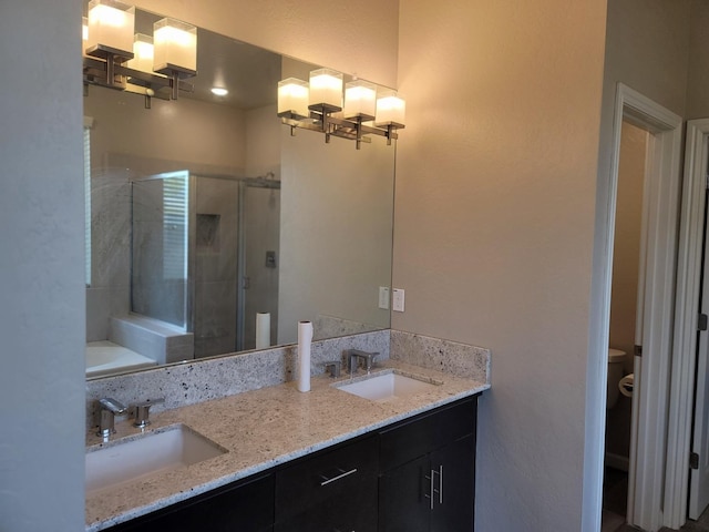 bathroom with double vanity, toilet, a shower stall, and a sink