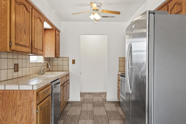 4462 N Manila Ave, Fresno, CA 93727 - kitchen featuring stainless steel appliances, tile countertops, decorative backsplash, ceiling fan, and dark floors