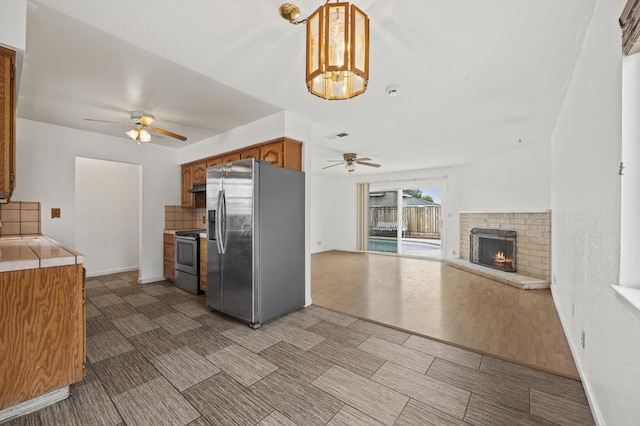 4462 N Manila Ave, Fresno, CA 93727 - kitchen featuring stainless steel appliances, ceiling fan, tile countertops, under cabinet range hood, and decorative backsplash