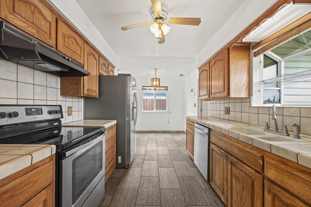 4462 N Manila Ave, Fresno, CA 93727 - kitchen with appliances with stainless steel finishes, tile counters, under cabinet range hood, and ceiling fan