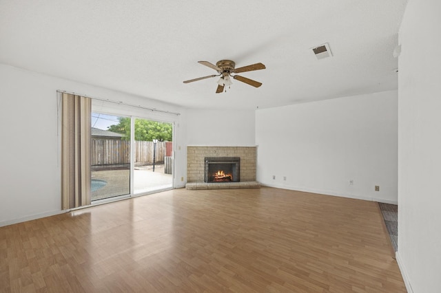 4462 N Manila Ave, Fresno, CA 93727 - unfurnished living room with ceiling fan, wood finished floors, and a brick fireplace