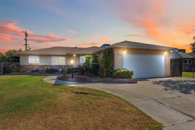 ranch-style house with an attached garage, fence, stucco siding, concrete driveway, and a lawn