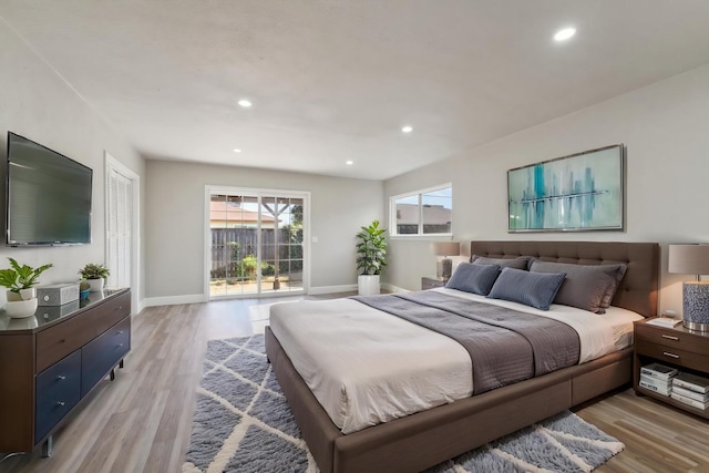 bedroom featuring access to outside, light wood finished floors, and multiple windows