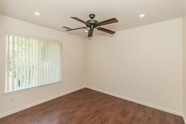 unfurnished room featuring baseboards, a ceiling fan, dark wood finished floors, and visible vents