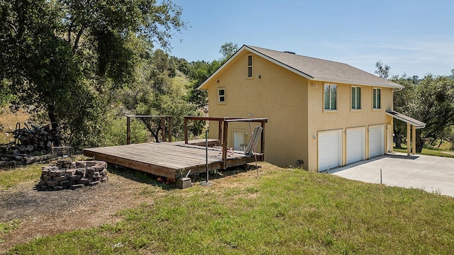 view of home's exterior with an attached garage, an outdoor fire pit, a wooden deck, stucco siding, and driveway