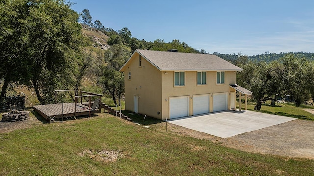 view of home's exterior featuring stucco siding, a yard, a deck, and concrete driveway