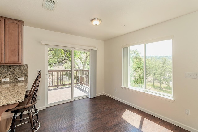 unfurnished dining area featuring visible vents, baseboards, and dark wood-type flooring