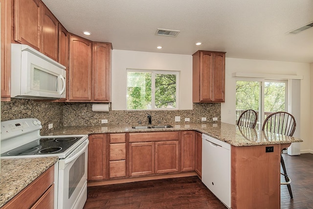 kitchen featuring a sink, a peninsula, a wealth of natural light, and white appliances