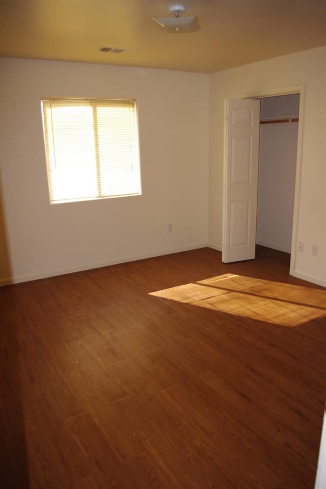 unfurnished bedroom featuring baseboards, wood finished floors, and visible vents