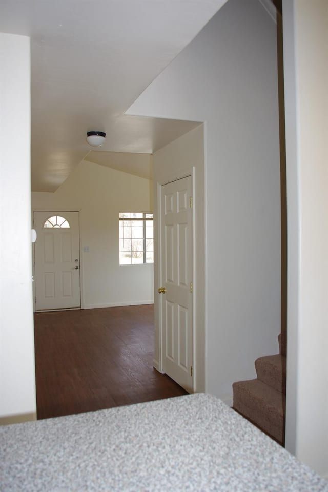 foyer entrance featuring stairway, baseboards, vaulted ceiling, and wood finished floors