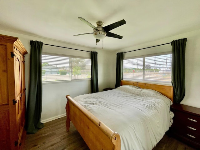 bedroom featuring baseboards, dark wood finished floors, multiple windows, and ceiling fan