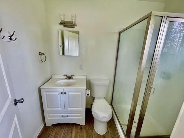 full bath featuring vanity, toilet, baseboards, a shower stall, and wood finished floors