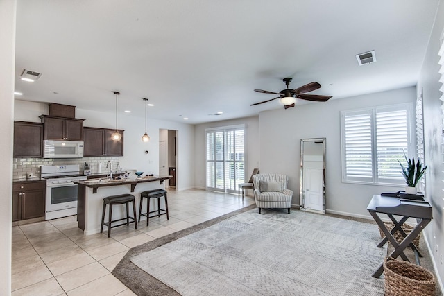 living area with baseboards, a ceiling fan, light tile patterned flooring, and visible vents