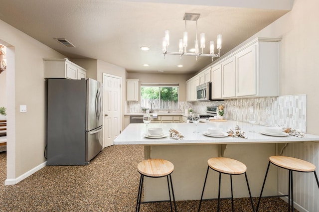 4650 W Chennault Ave, Fresno, CA 93722 - kitchen featuring stainless steel appliances, a peninsula, baseboards, tasteful backsplash, and white cabinets