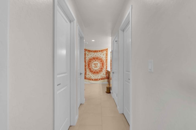 hall with baseboards, recessed lighting, and light tile patterned flooring