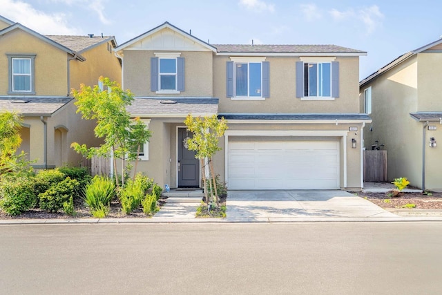 traditional-style home featuring fence, a shingled roof, a garage, stucco siding, and driveway