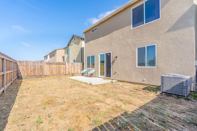rear view of house featuring a fenced backyard, central AC unit, stucco siding, and a patio area