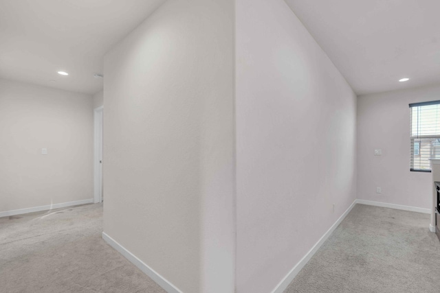 hallway featuring baseboards, light carpet, and recessed lighting