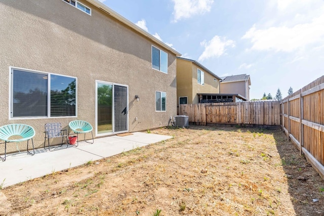 rear view of house with a fenced backyard, a patio area, stucco siding, and central AC unit