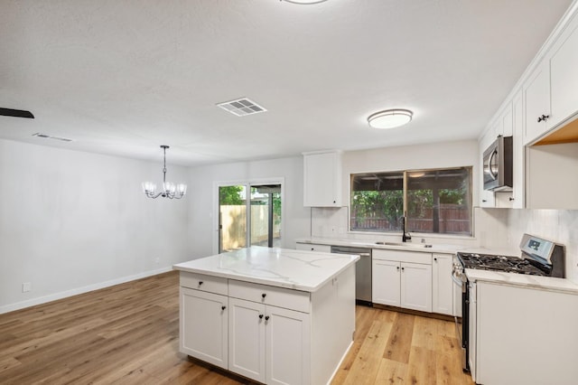 kitchen featuring appliances with stainless steel finishes, a sink, visible vents, and a center island