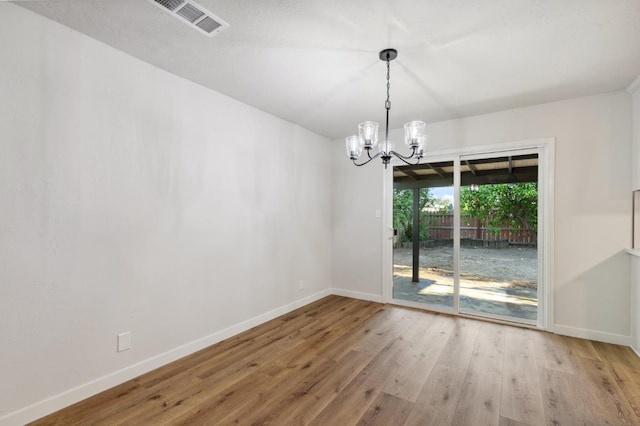 unfurnished dining area featuring baseboards, visible vents, wood finished floors, and a notable chandelier