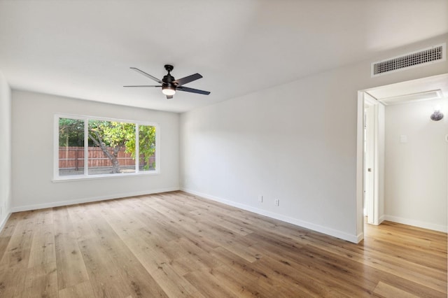 spare room featuring a ceiling fan, baseboards, visible vents, and wood finished floors