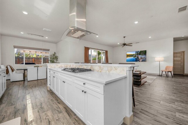 855 Groveland Ave W, Madera, CA 93636 - kitchen with visible vents, wall chimney exhaust hood, white cabinetry, stainless steel gas stovetop, and light wood-style flooring