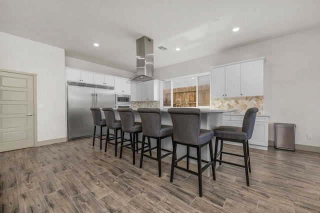 855 Groveland Ave W, Madera, CA 93636 - kitchen featuring island exhaust hood, dark wood finished floors, built in appliances, and backsplash