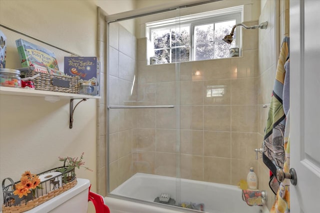 bathroom with toilet and shower / bath combination with glass door