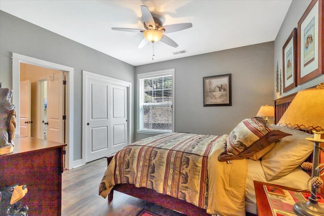 bedroom with ceiling fan, visible vents, and wood finished floors